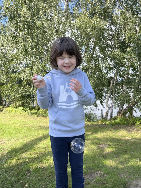 Das Bild zeigt ein kleines Mädchen in einem hellblauen Hoodie mit weißem Wolfsburg-Wappen.